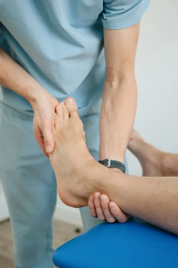 Kinésithérapeute qui mobilise la cheville d'un patient