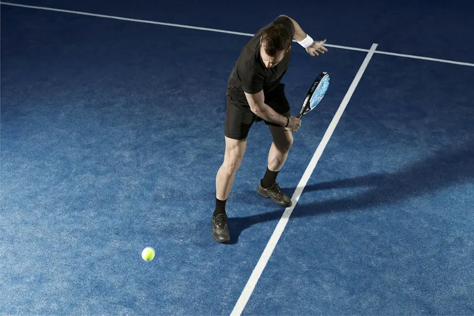 Joueur de padel en revers sur un court bleu